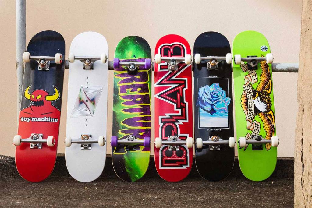 A young skater does an ollie on a colorful WhiteFang complete skateboard at a busy skate park